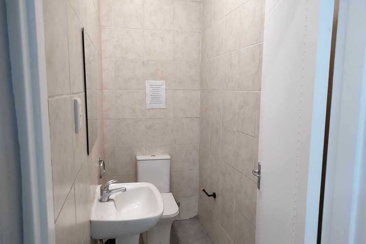 A compact bathroom featuring full-height wall tiling, a pedestal basin, and a standard toilet suite.