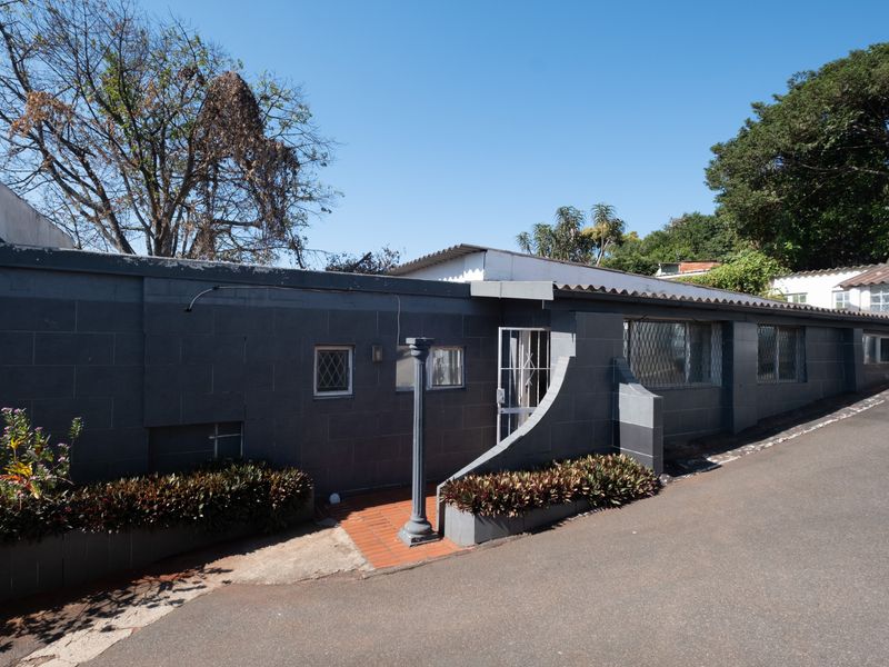 Exterior view of the office building facade featuring a dark masonry wall, security gates, and a paved entrance walkway.