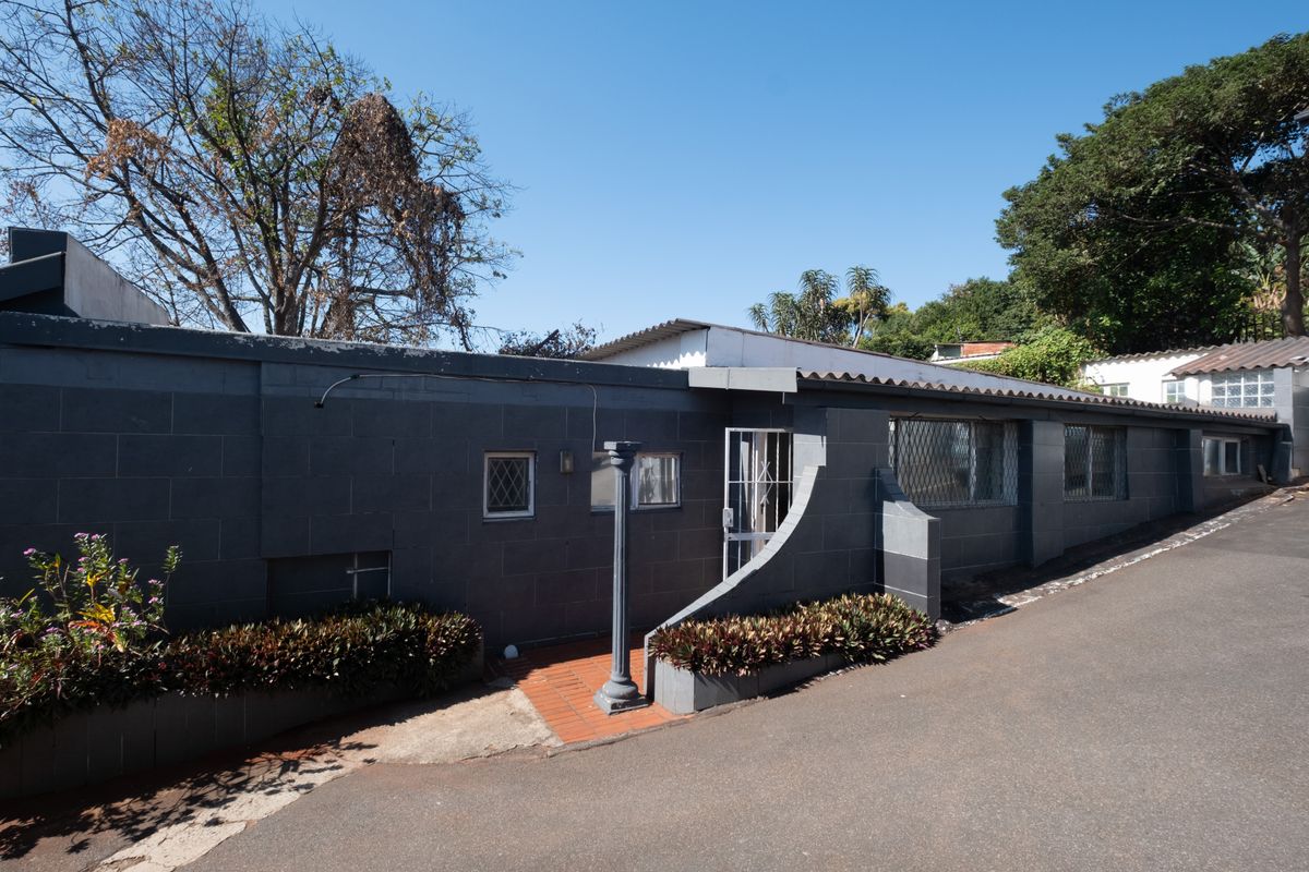 Exterior view of the office building facade featuring a dark masonry wall, security gates, and a paved entrance walkway.