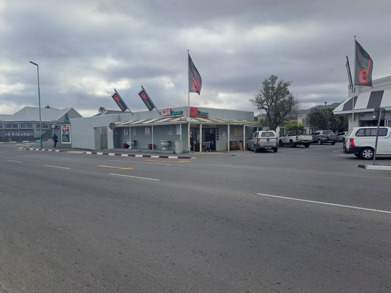 Street-level view of a commercial liquor store property featuring a covered veranda, paved parking area, and prominent signage.