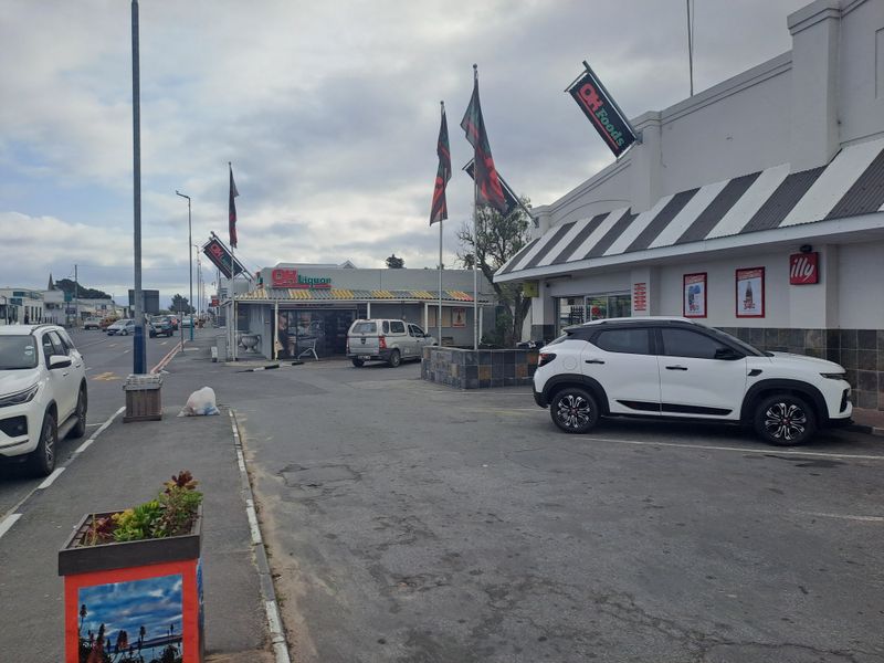 Exterior view of a commercial retail property featuring a paved parking area, prominent signage, and striped metal awnings.