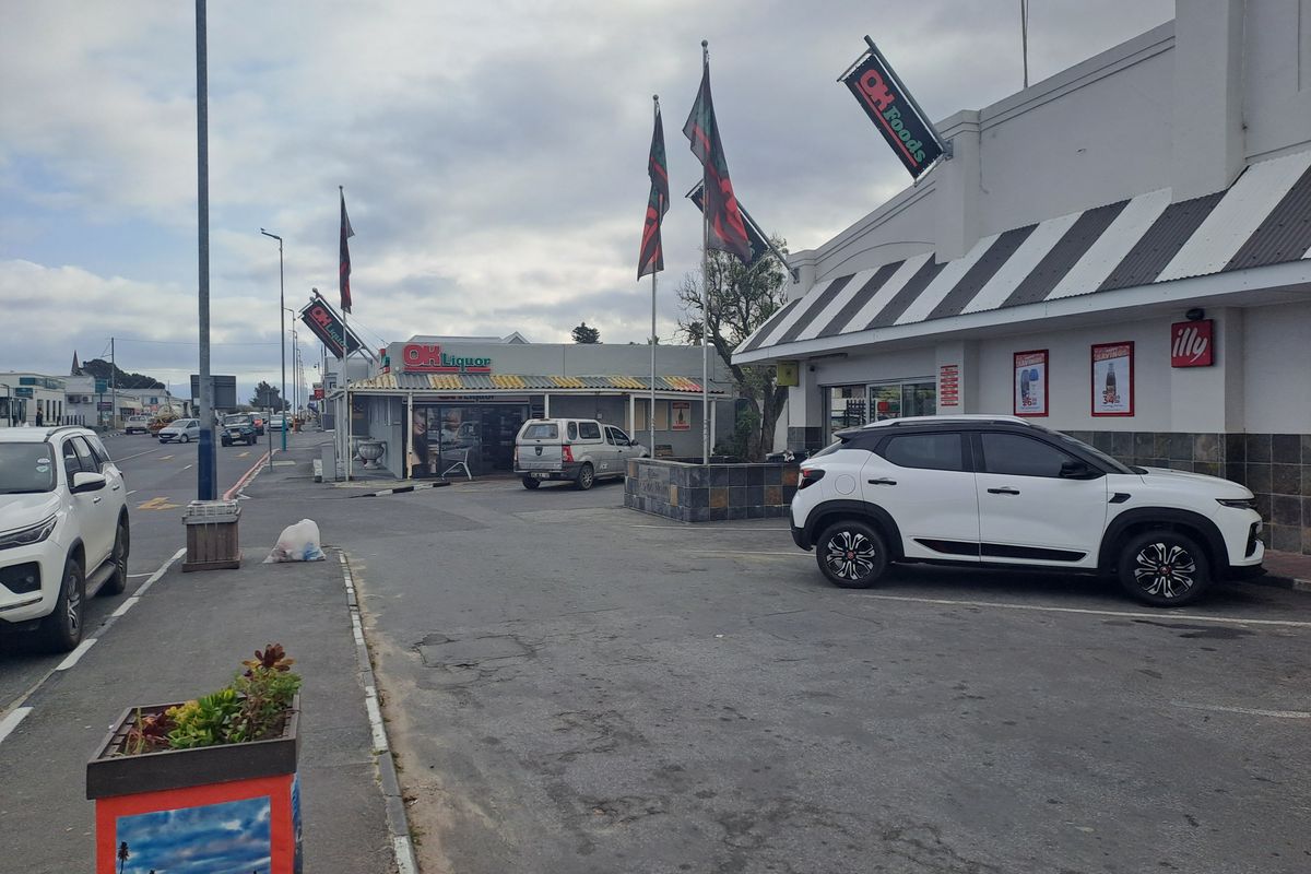 Exterior view of a commercial retail property featuring a paved parking area, prominent signage, and striped metal awnings.