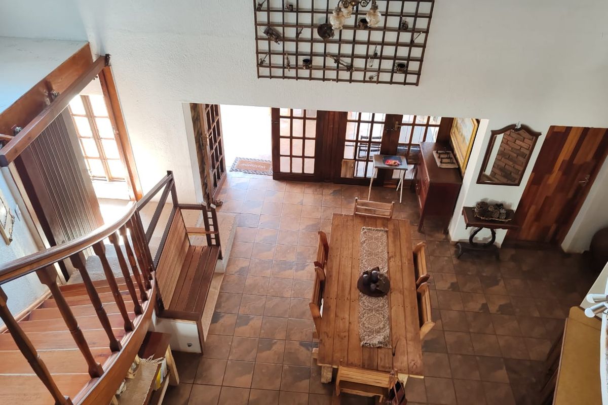 An elevated view of a living and dining area featuring tiled floors, a wooden staircase with a balustrade, and access to the exterior via french doors.