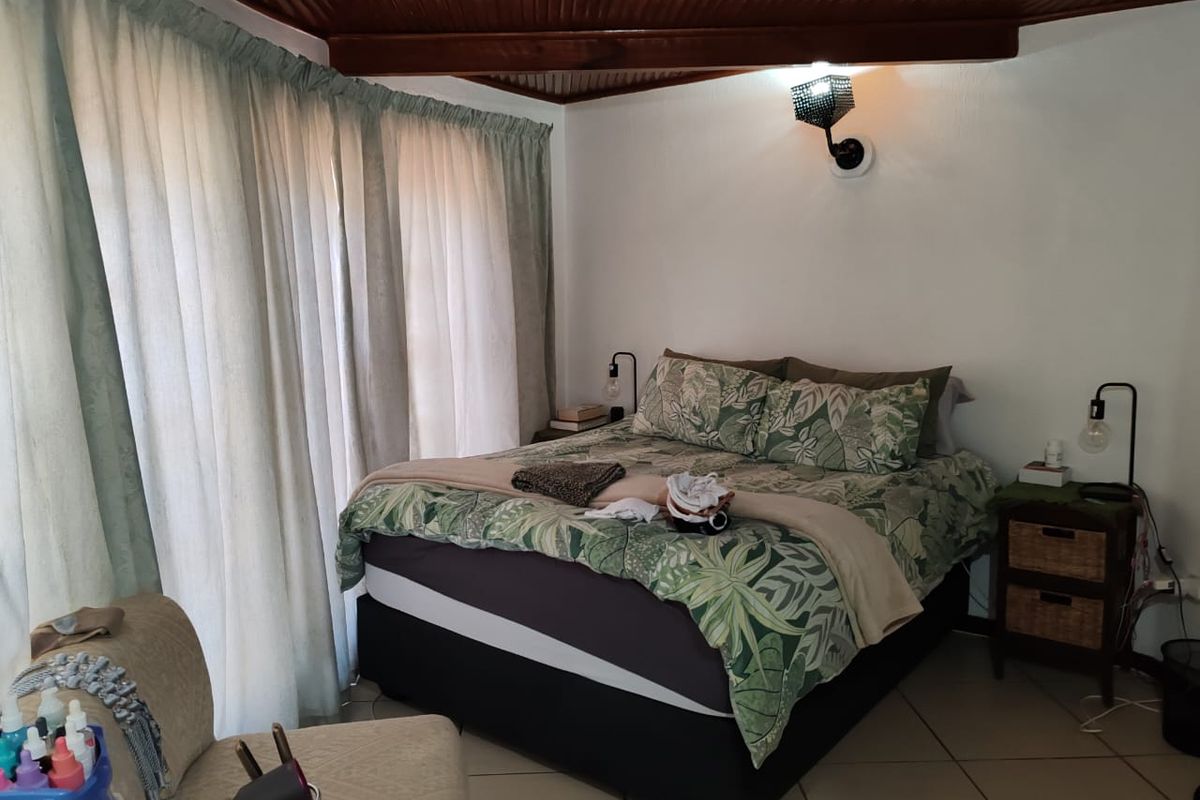A cozy bedroom featuring tiled flooring and a distinctive timber tongue and groove ceiling, providing a warm and rustic atmosphere.