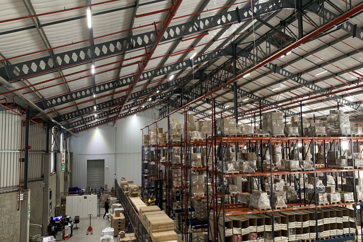Spacious industrial warehouse featuring high-clearance steel truss roofing, integrated fire sprinkler systems, and extensive heavy-duty pallet racking for efficient storage and logistics operations.