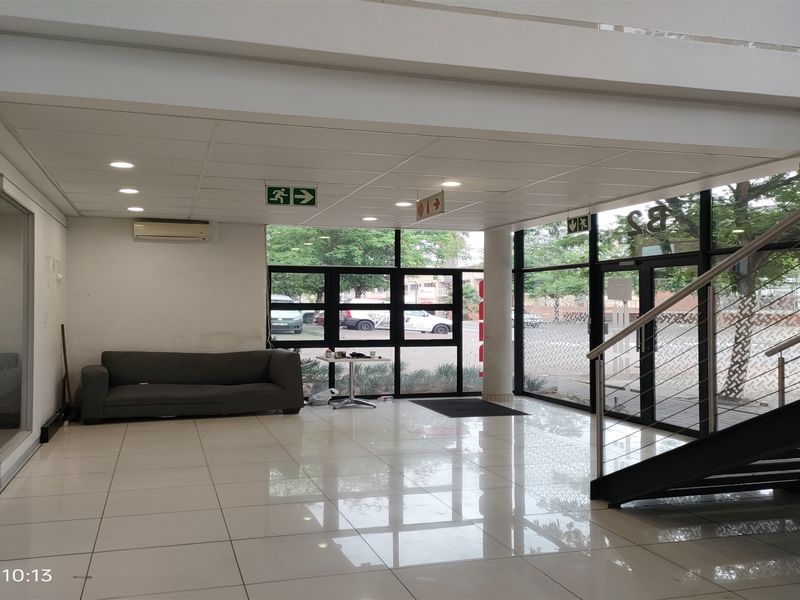 Spacious industrial entrance lobby featuring polished tiled flooring, a modern metal staircase, and extensive glass frontage providing ample natural light.