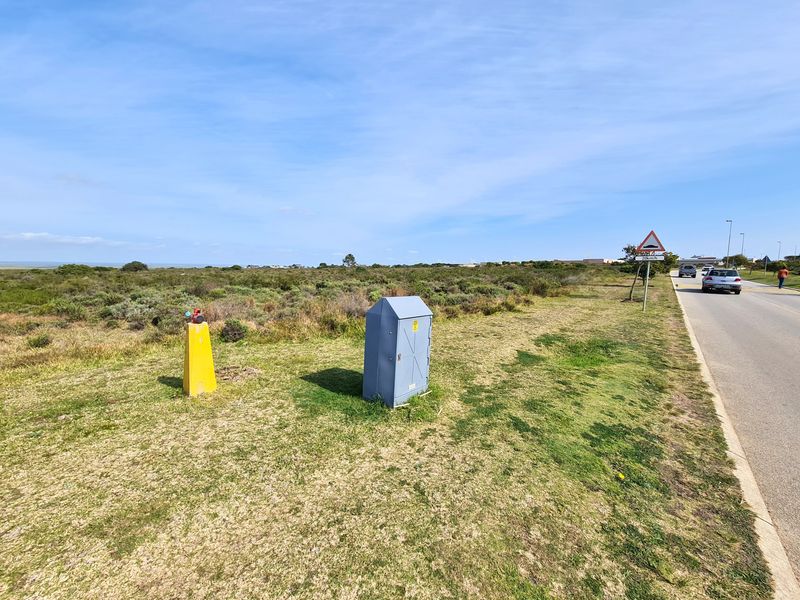 Street-level view of the vacant commercial land showing roadside access, utility infrastructure, and surrounding natural landscape.