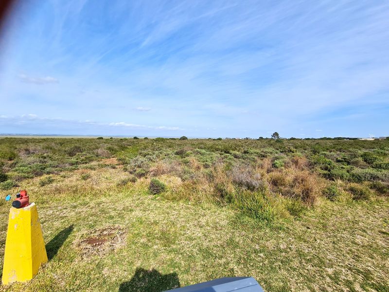 An expansive view of undeveloped commercial land featuring native vegetation and a visible fire hydrant in the foreground.