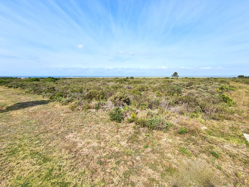A wide-angle view of the vacant commercial land featuring natural coastal vegetation and an expansive horizon.