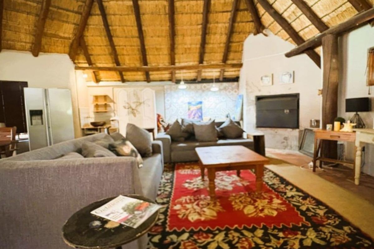 Spacious living area featuring a high vaulted thatched roof with exposed timber rafters and a built-in fireplace.