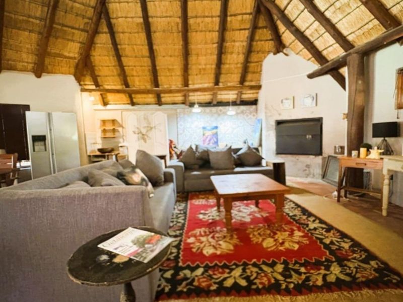 Spacious living area featuring a high vaulted thatched roof with exposed timber rafters and a built-in fireplace.