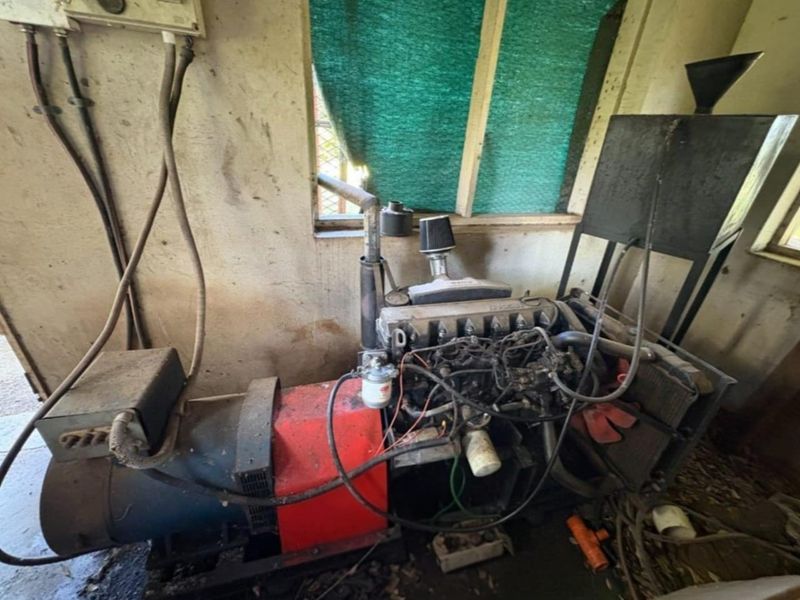 A utility space housing a large industrial diesel generator, showing signs of wear and requiring maintenance.