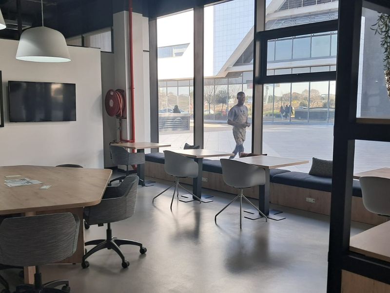 Modern open-plan office space featuring floor-to-ceiling windows, built-in bench seating, and polished concrete floors, offering a bright and professional work environment.