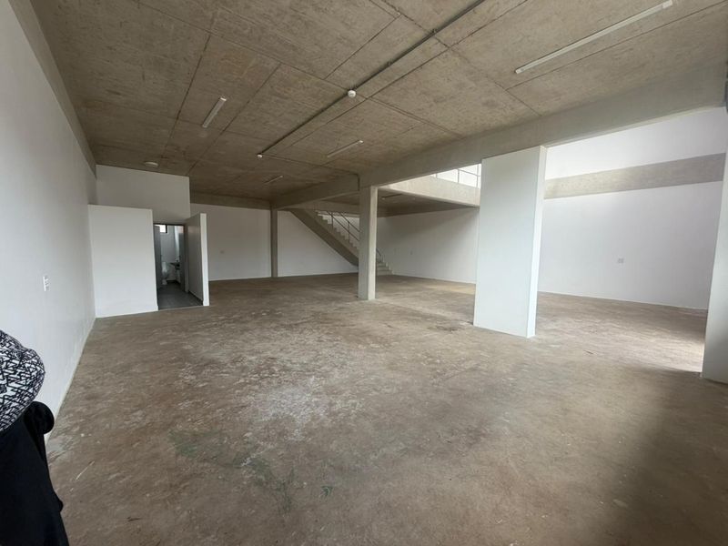 Spacious open-plan industrial unit featuring exposed concrete ceilings, polished concrete floors, and an internal staircase, offering a versatile blank canvas for commercial use.