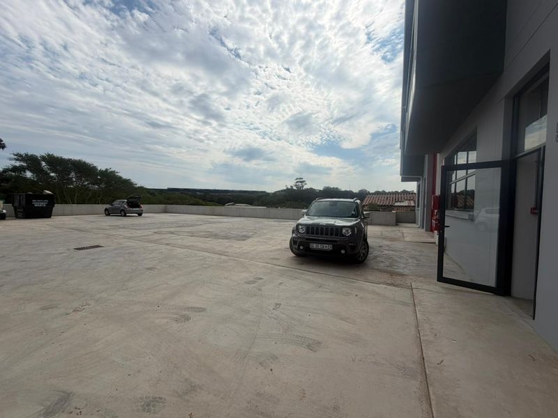 A spacious concrete paved rear yard area of an industrial property, featuring perimeter walling and direct access to the building.