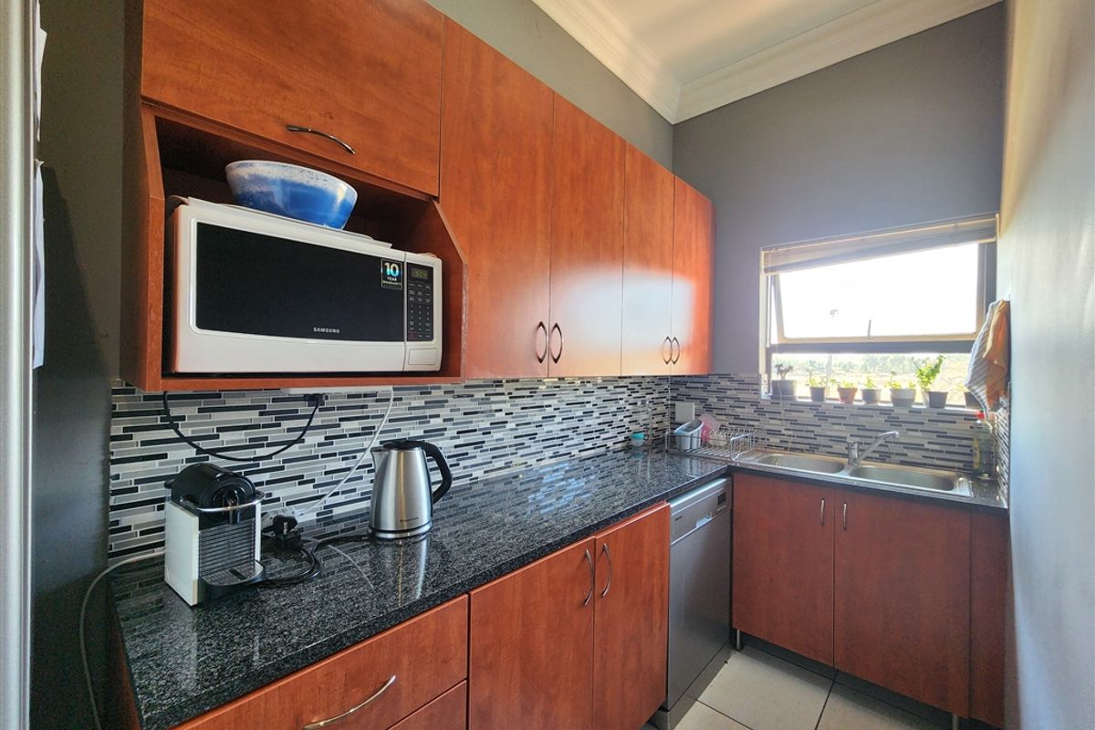 A functional kitchen featuring wood-finish cabinetry, granite countertops, a mosaic tile backsplash, and a double-basin sink with a window view.