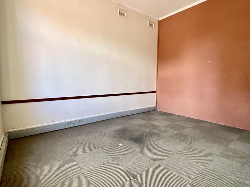 An empty office space featuring carpet tiles, air conditioning vents, and a dual-tone wall finish, suitable for a professional workspace.