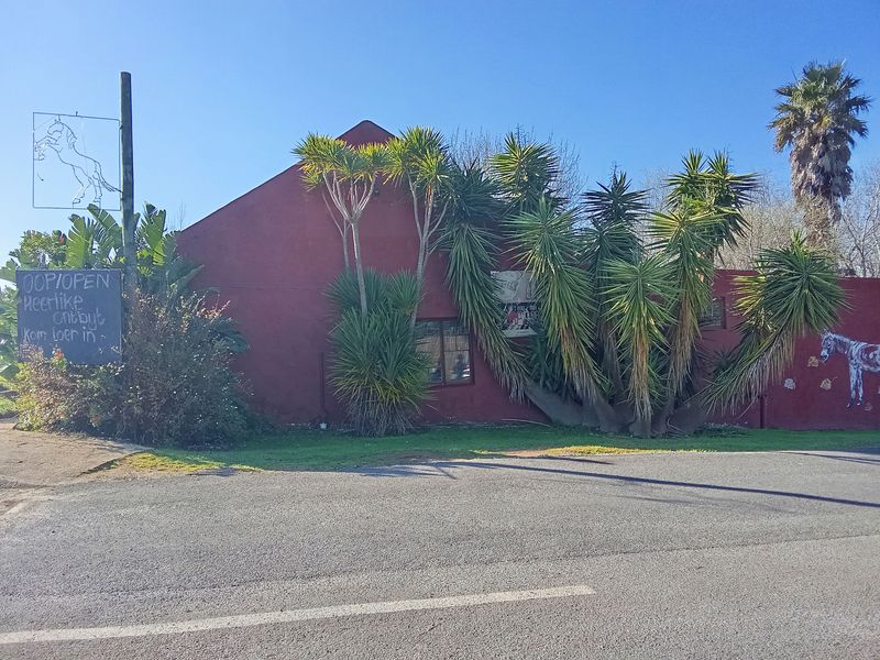 Street-facing view of the restaurant exterior featuring a red facade, signage, and established garden landscaping.