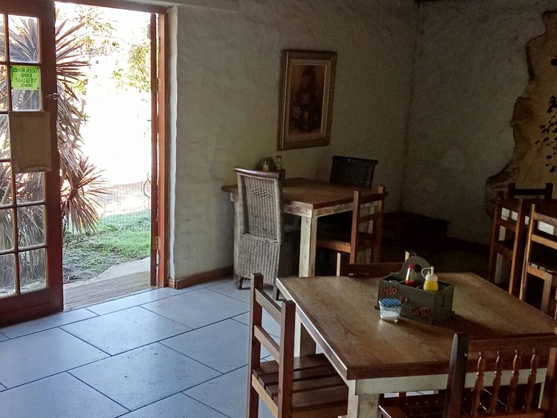 A rustic dining area featuring textured plaster walls, tiled flooring, and direct access to the outdoors through wooden french doors.