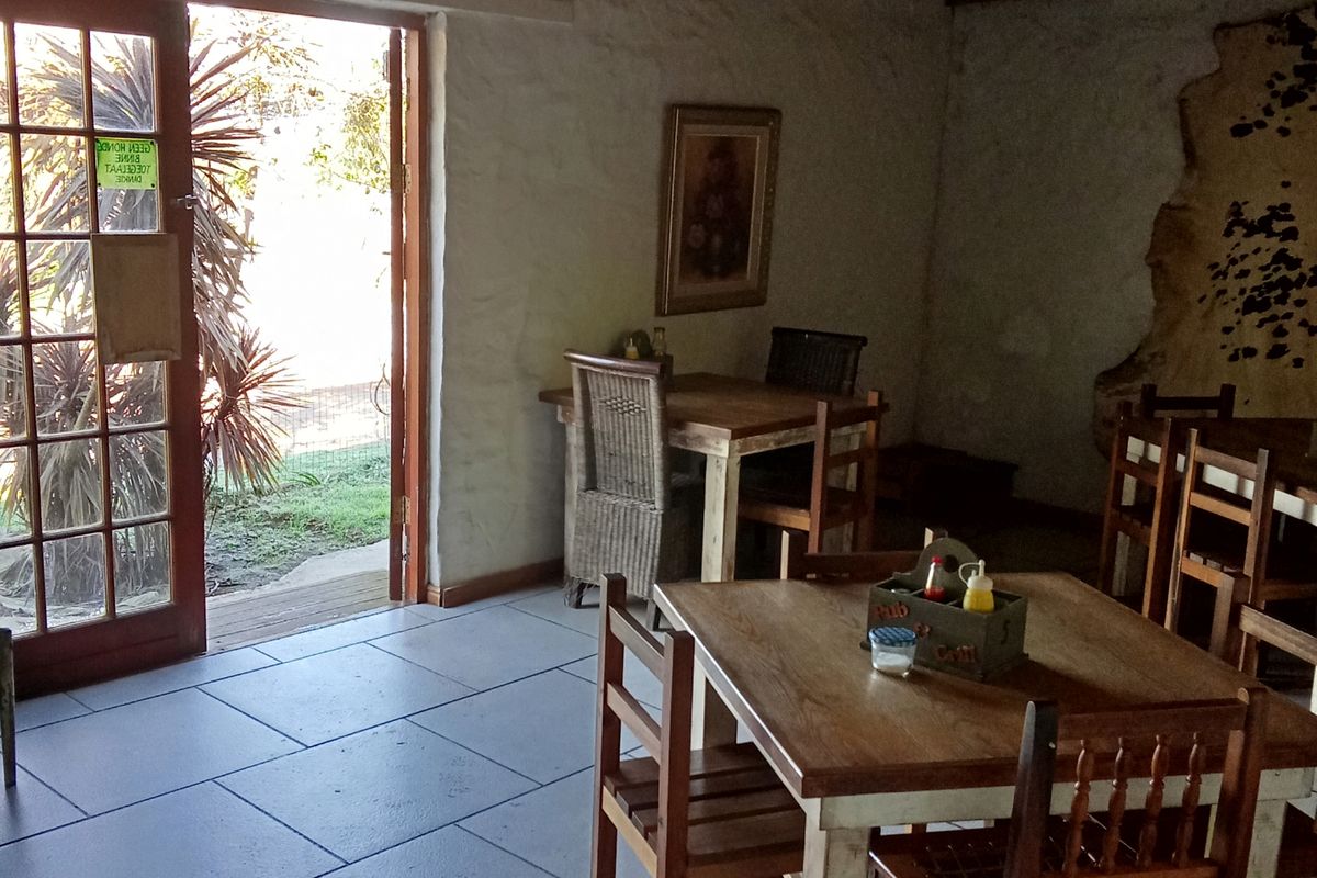 A rustic dining area featuring textured plaster walls, tiled flooring, and direct access to the outdoors through wooden french doors.
