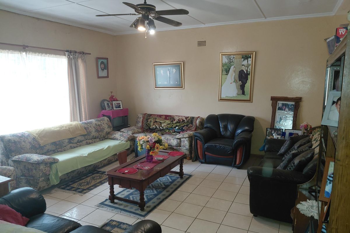 A spacious living room featuring tiled flooring and a ceiling fan, offering a functional layout ready for modern updates and cosmetic improvements.