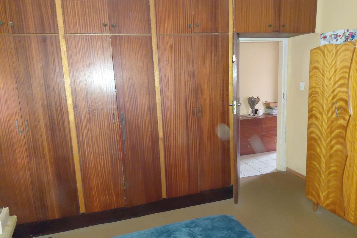Bedroom featuring extensive floor-to-ceiling built-in wooden cabinetry and a doorway leading to an adjacent room with tiled flooring.