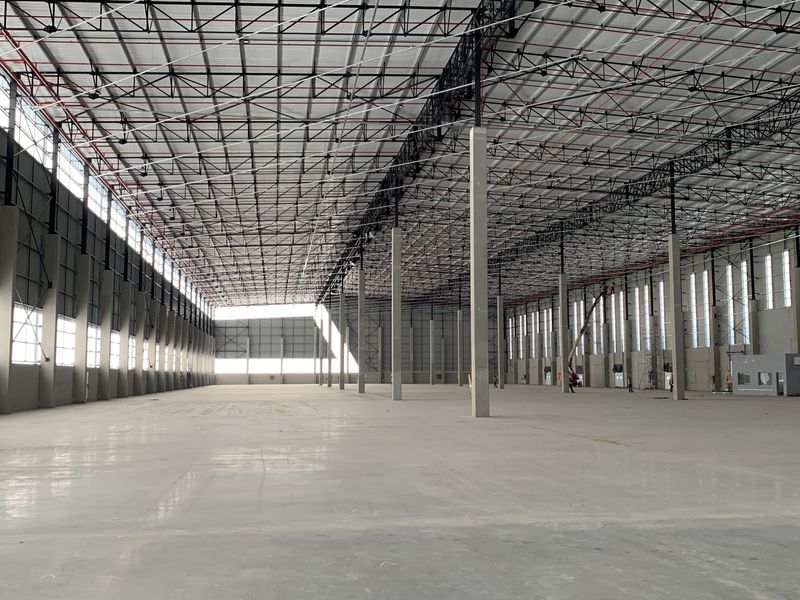 Expansive industrial warehouse space featuring high ceilings with exposed steel trusses, polished concrete flooring, and integrated fire sprinkler systems.