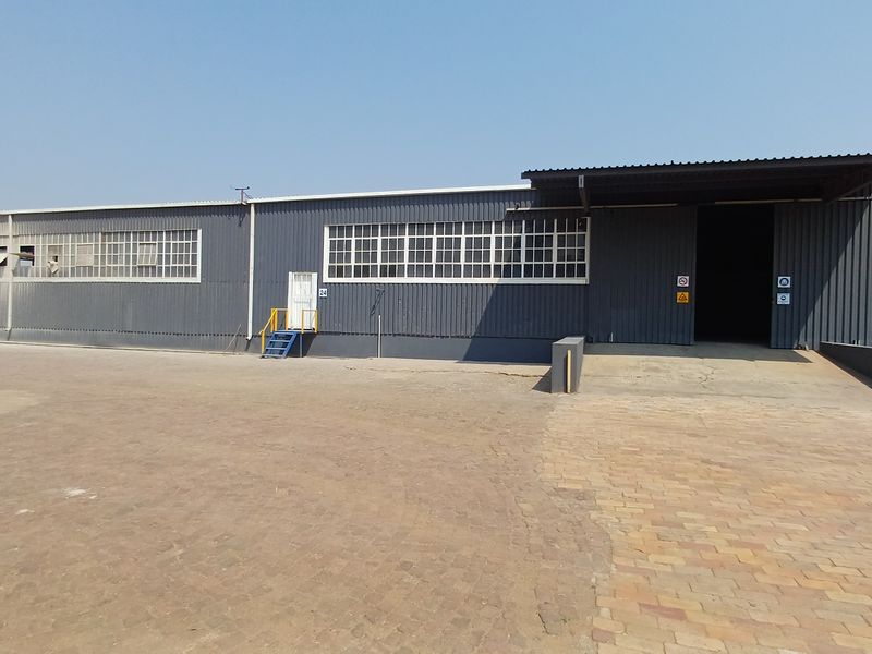 Industrial warehouse exterior featuring corrugated metal cladding, large loading bay access, and a spacious paved yard area.