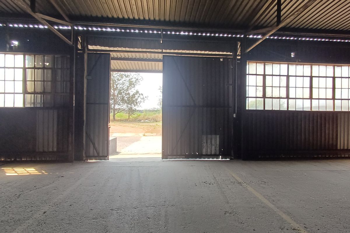 Spacious industrial utility area featuring high corrugated metal ceilings, large steel-framed windows, and expansive sliding doors opening to the exterior.
