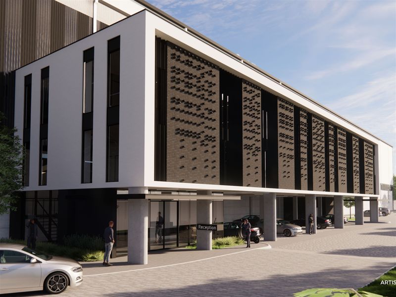 Modern industrial office building exterior featuring a contemporary facade with textured brickwork, glass entrance, and covered reception area.