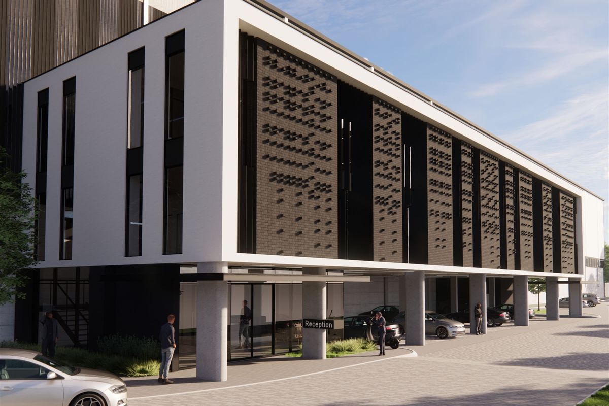 Modern industrial office building exterior featuring a contemporary facade with textured brickwork, glass entrance, and covered reception area.