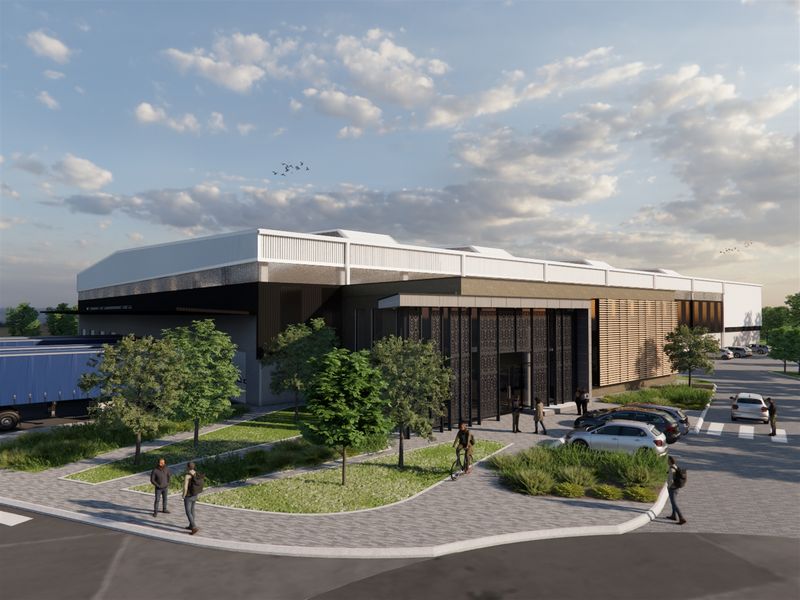 A modern industrial facility featuring a contemporary facade with decorative metal screens, paved parking areas, and integrated loading bays.