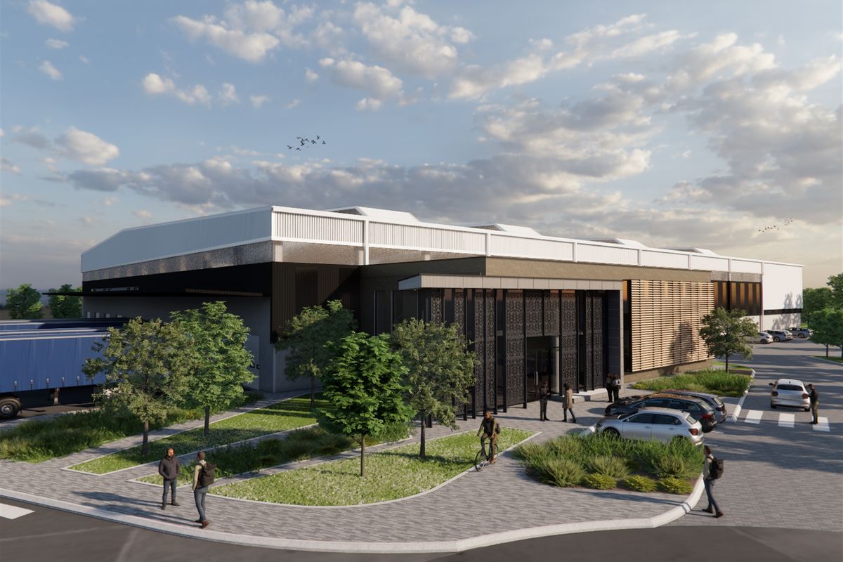 A modern industrial facility featuring a contemporary facade with decorative metal screens, paved parking areas, and integrated loading bays.
