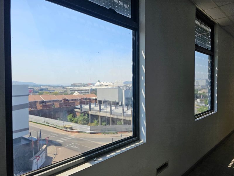 An empty office space featuring large windows with natural light and views of the surrounding urban area.