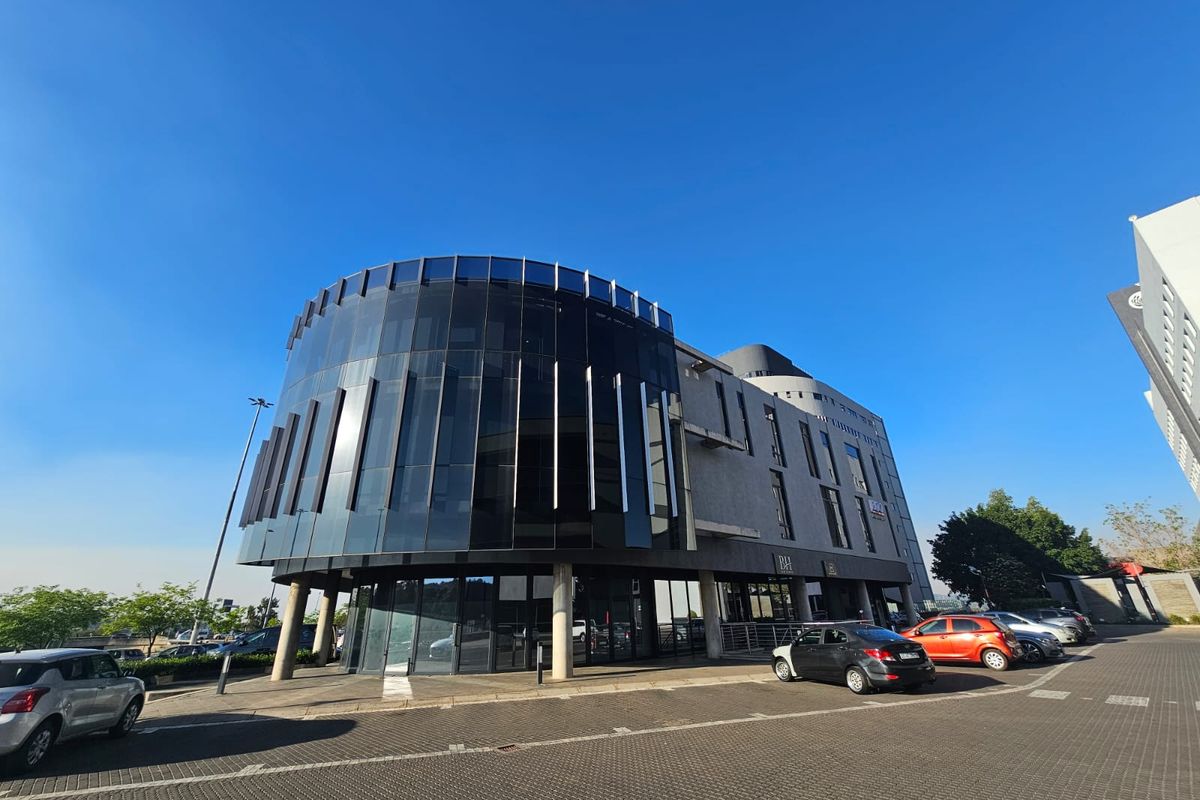 Modern multi-story office building featuring a prominent curved glass facade and integrated ground-level parking area.