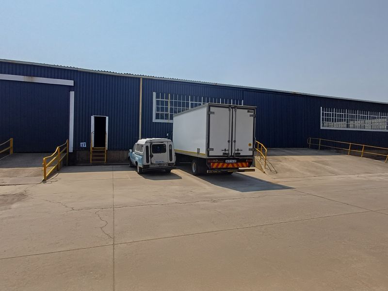 Industrial warehouse exterior featuring multiple loading docks, concrete loading apron, and blue metal cladding with steel access ramps.
