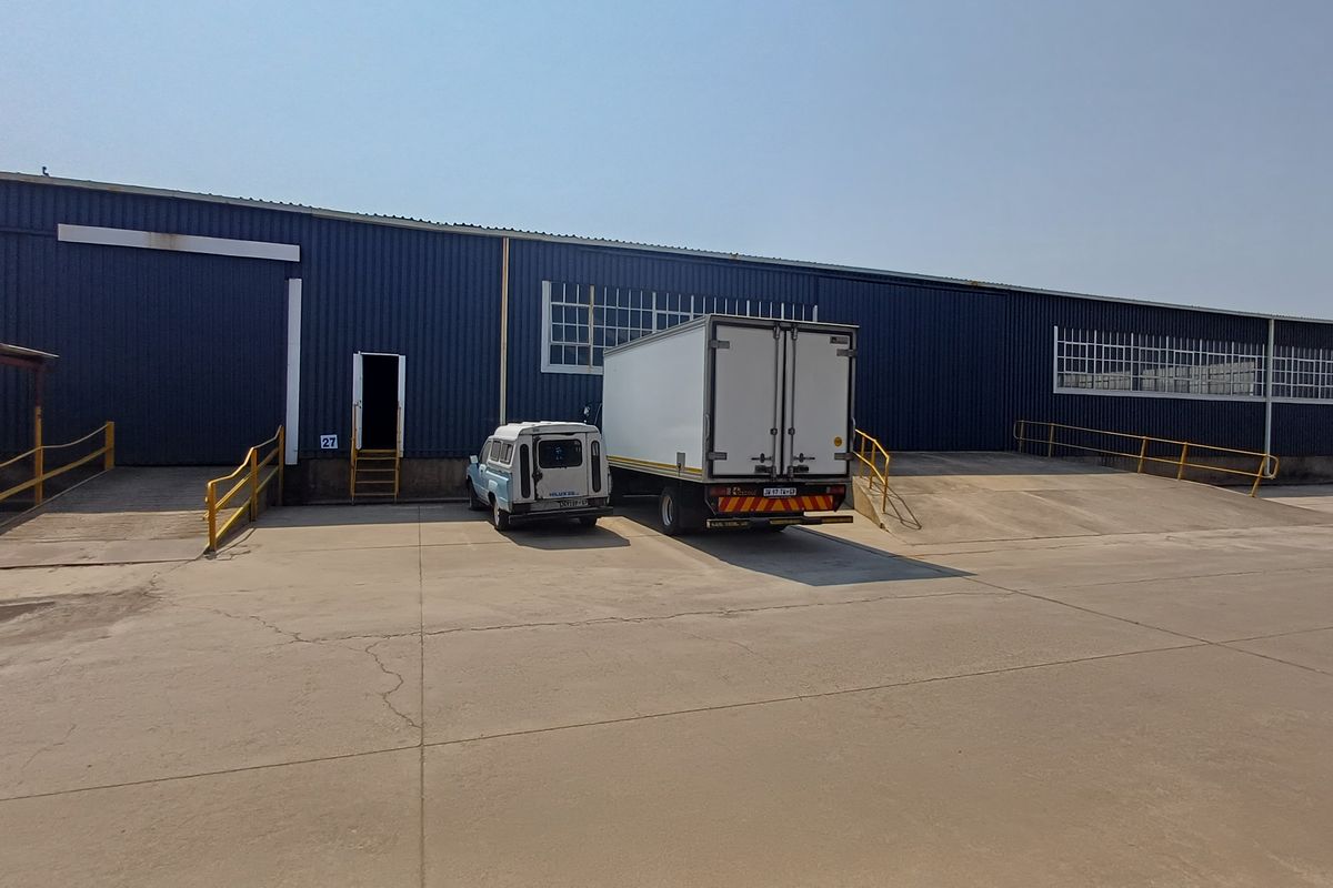 Industrial warehouse exterior featuring multiple loading docks, concrete loading apron, and blue metal cladding with steel access ramps.
