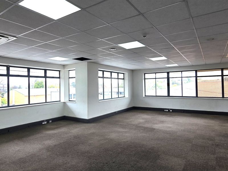 Spacious, open-plan office area featuring large windows, suspended ceilings with integrated lighting, cassette air conditioning, and carpeted flooring.