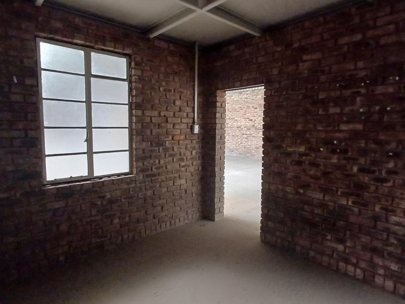 An industrial-style utility space featuring exposed brick walls, steel-framed windows, and exposed ceiling beams, offering a raw, unfinished aesthetic.