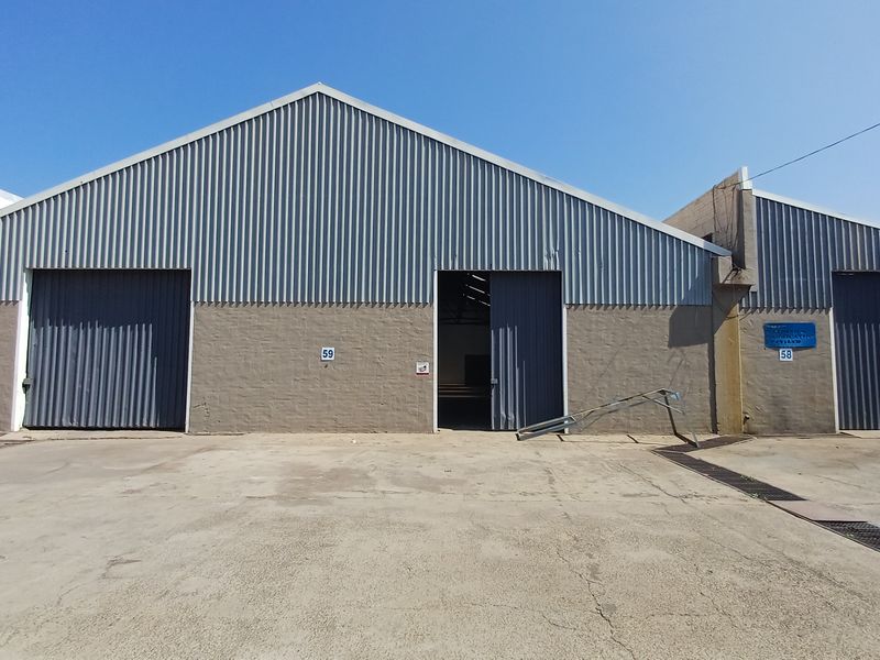Industrial warehouse exterior featuring corrugated metal cladding, large sliding access doors, and a concrete yard area.
