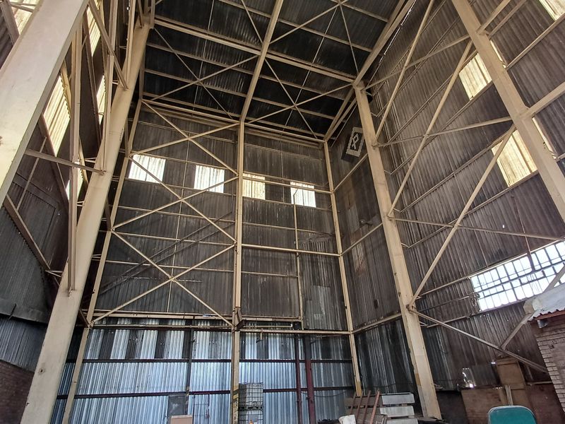A high-volume industrial utility space featuring exposed steel structural framing, corrugated metal wall cladding, and high-level clerestory windows providing natural light.