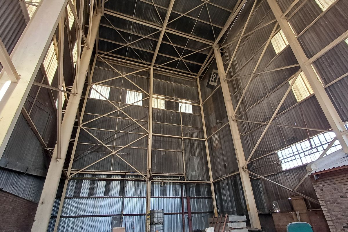 A high-volume industrial utility space featuring exposed steel structural framing, corrugated metal wall cladding, and high-level clerestory windows providing natural light.
