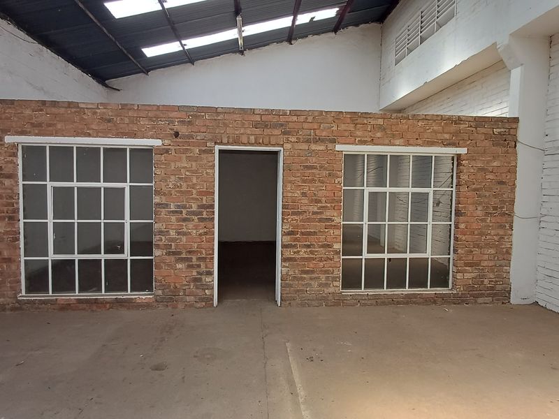 Industrial utility space featuring exposed brick partition walls, steel-framed windows, concrete flooring, and high ceilings with integrated skylights.