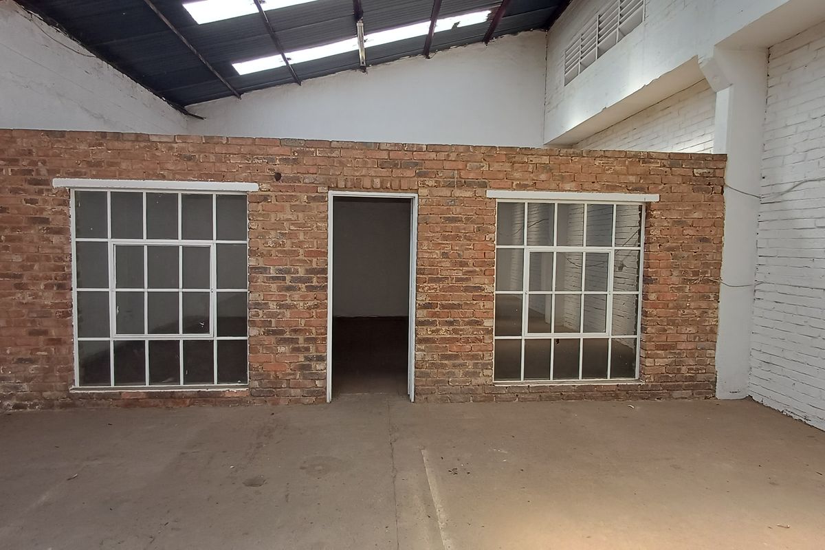 Industrial utility space featuring exposed brick partition walls, steel-framed windows, concrete flooring, and high ceilings with integrated skylights.