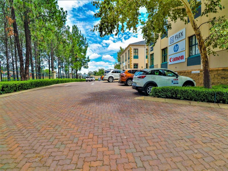 Exterior view of a commercial office building featuring a paved parking area, mature landscaping, and prominent corporate signage on the building facade.