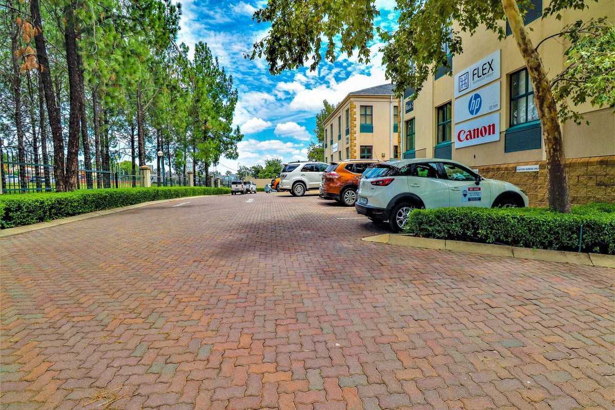 Exterior view of a commercial office building featuring a paved parking area, mature landscaping, and prominent corporate signage on the building facade.