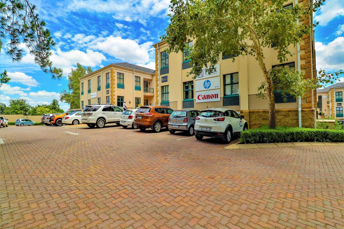 Exterior view of a multi-story office building featuring a paved parking area and established landscaping.