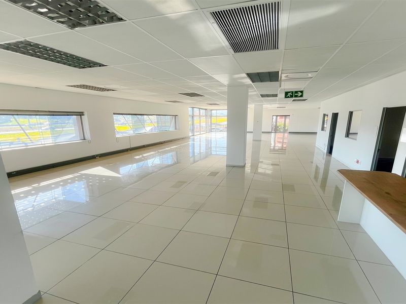 Spacious, open-plan office area featuring polished tiled floors, suspended ceilings with integrated lighting, air conditioning, and a built-in reception counter.