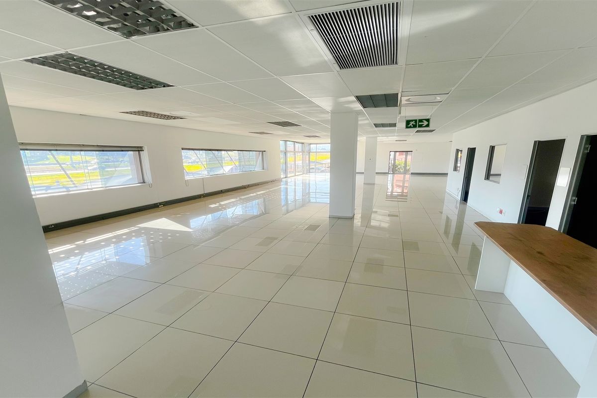 Spacious, open-plan office area featuring polished tiled floors, suspended ceilings with integrated lighting, air conditioning, and a built-in reception counter.