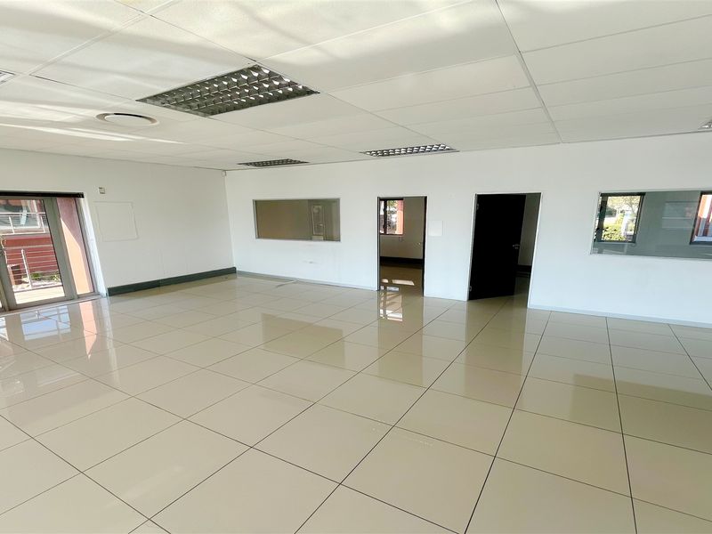 Spacious, open-plan office area featuring polished ceramic floor tiles, suspended ceilings with recessed lighting, and integrated glass partitions for a bright, professional workspace.